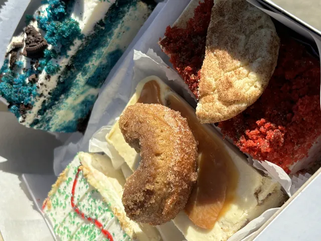 A box packed with blue velvet, red velvet, cookies and a cinnamon churro