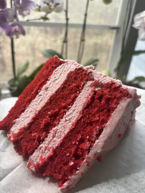 A strawberry red velvet layer cake slice cut to show the layers