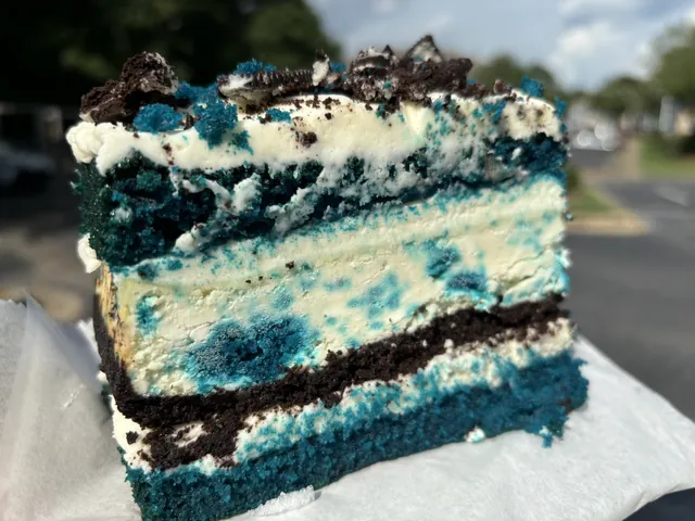 A blue velvet cookies and cream cheesecake slice cut to show the layers