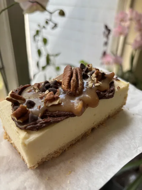 A turtle cheesecake slice with pecans and caramel