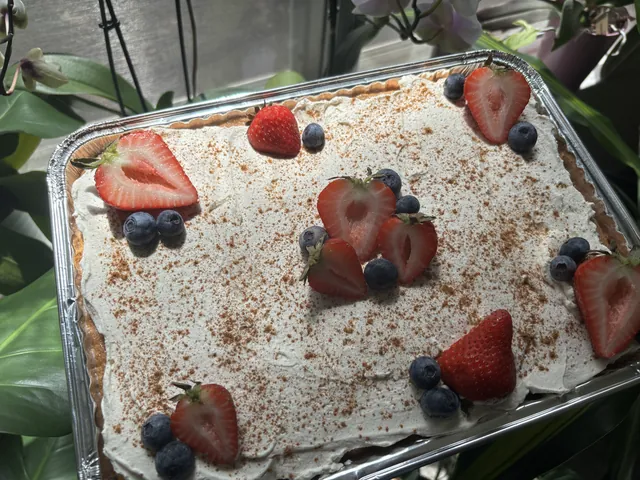A full pan dusted with cinnamon and set with strawberries and blueberries