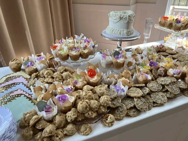 An event table crowded with cookies, dessert cups and a tiered cake