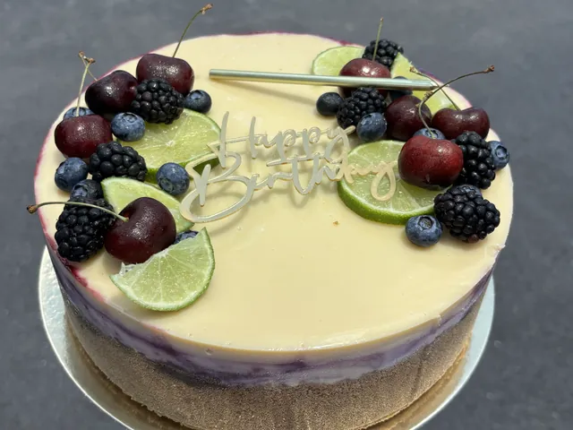 A whole blueberry cheesecake crowned with limes, cherries and blackberries