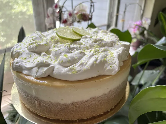 A whole key lime cheesecake under whipped cream and zest
