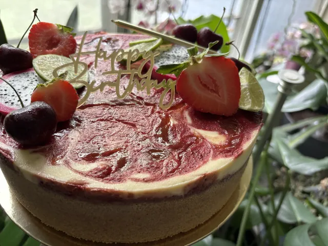 A whole raspberry swirl cheesecake with cherries and strawberry
