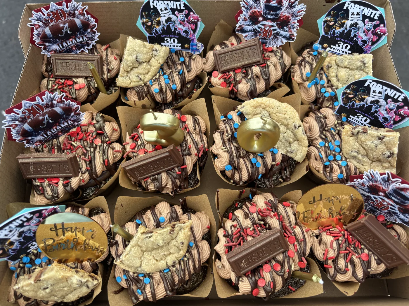 A box of loaded cupcakes finished with chocolate and cookies