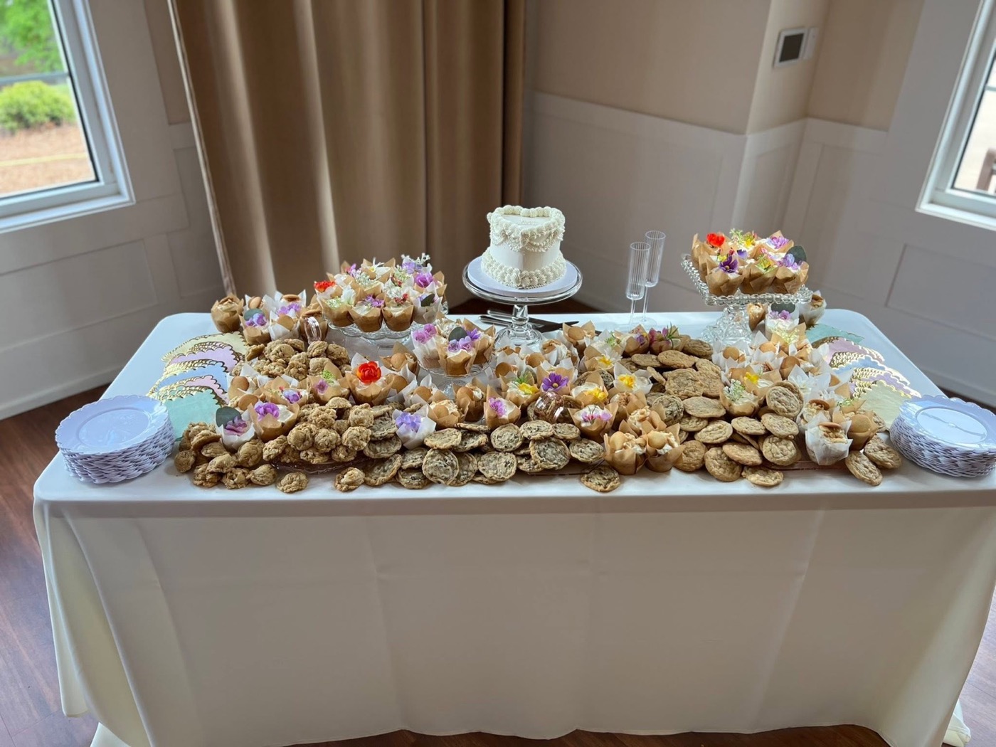 A long white table crowded end to end with cookies and dessert cups
