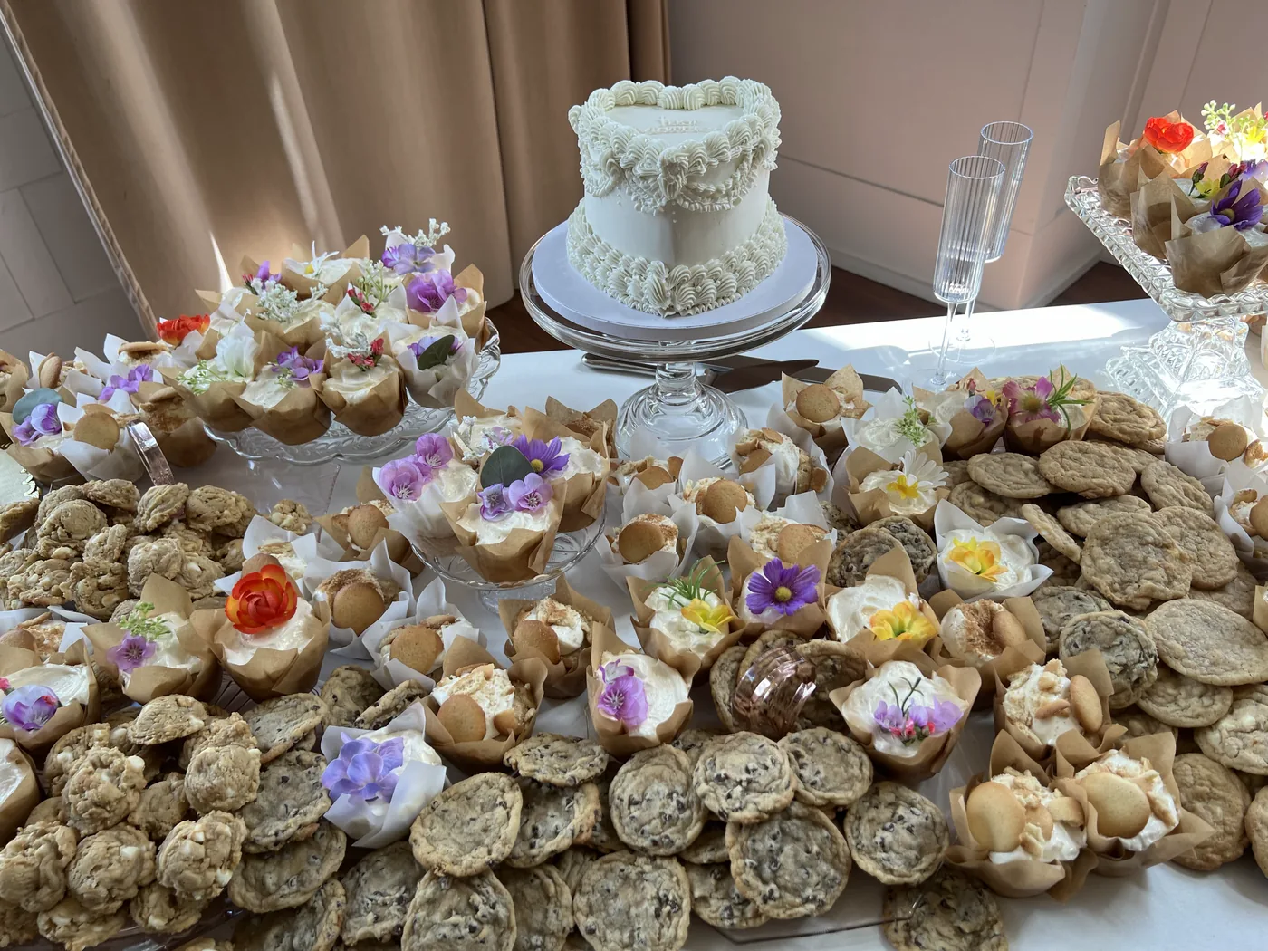 A dessert table built out with cookies, cups and a piped cake